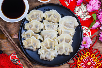 Chinese Jiaozi new year food, spring festival food on traditional spring festival Spring festival atmosphere and dumplings, ang pow or red packet and gold ingots. Chinese characters means luck,wealth
