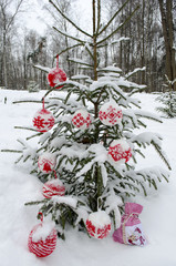 Knitted balls for New Year and Christmas tree decoration hanging on spruce covered with snow