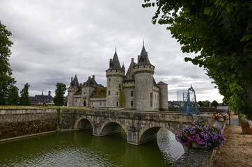 Fototapeta premium Castle of Sully-sur-Loire, Loire region, France. Snap of 30 June 2017 at 18:21. Captured at the entrance of the castle park. White clouds moving on blue sky. Towers well visible in the image.