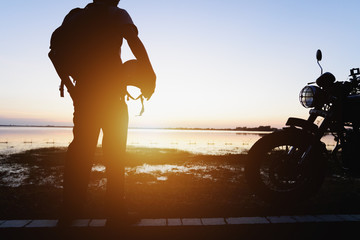 Silhouette of biker and motorcycle with sunrise background, Rider moto trip on the street at the...