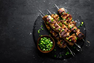 Rolgordijnen Eten Gegrilde vleesspiesjes, shish kebab op zwarte achtergrond, bovenaanzicht