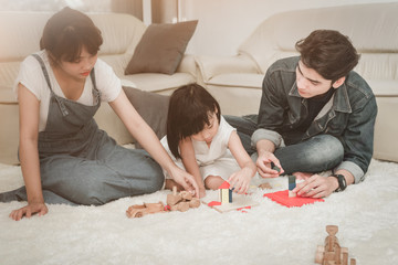 Happy family concept ,Happy Asian young family mother, father and daughter playing on carpet at home.