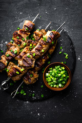 Grilled meat skewers, shish kebab on black background, top view