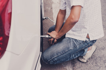 Accident with punctured tires. Traveler Man changing flat tire on the road. Replacing the tires on the car,  Attaching a spare wheel.