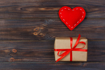 Heart and gift box with red ribbon on wooden background