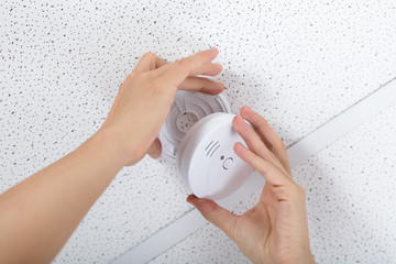 Person's Hand Installing Smoke Detector On Ceiling