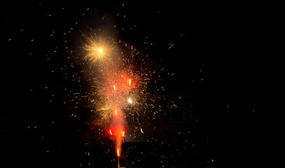 Red and yellow fireworks at night near house