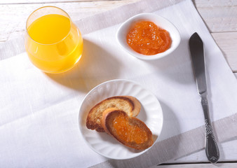 Morning Breakfast set with orange jam on bread toast and juice in glass.