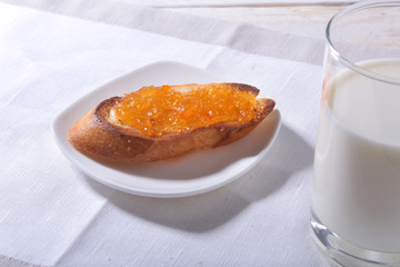 Morning Breakfast set with orange jam on bread toast and milk in glass.
