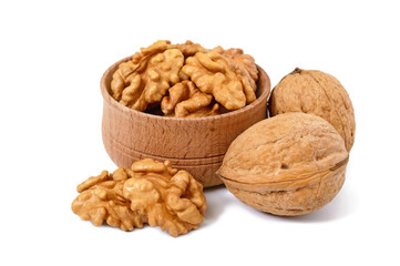 Walnuts kernels in a wooden bowl and whole nuts isolated on white background.