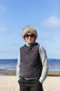 Portrait of woman on beach wearing sunglasses and fur hat