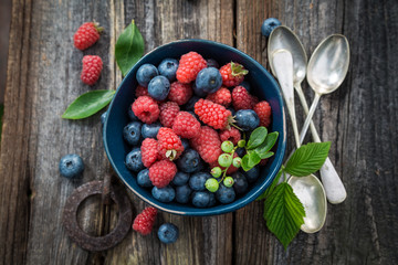 Ripe blueberries and raspberries on old wooden rustic table