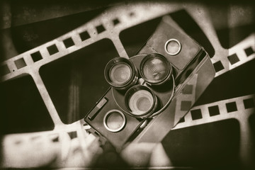 Old retro movie camera on background of perforation film