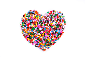Frame in the shape of hearts. Background of multicolored decorative plastic craft beads. 