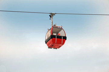 Red gondola car lift on the ski resort against blue sky - obrazy, fototapety, plakaty