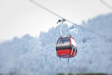 Fotobehang Red gondola car lift on the ski resort over forest trees © rilueda
