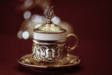 Traditional Turkish coffee in traditional metal cup on brown background with bokeh