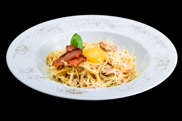 Pasta with egg, bacon and cheese in a white plate isolated on black background