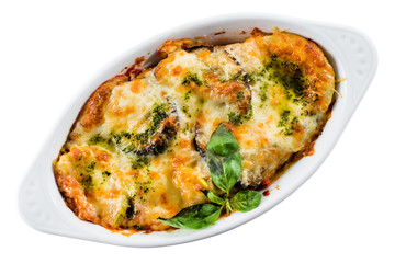 Traditional lasagna made with beef, Bolognese sauce topped with basil in a white plate isolated on white background. Top view, flat lay