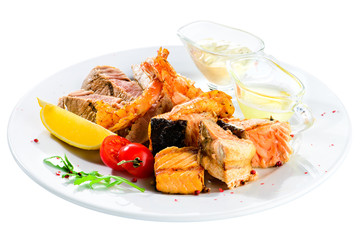 Appetizing Tuna steak with tomato, lemon and sauce in a white plate isolated on white background, close-up