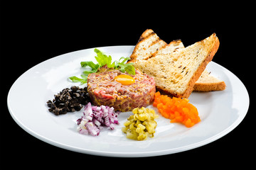 Tasty Beef Tartare with egg yolk, croutons and salad in a white plate isolated on white background, close-up