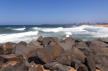 Fototapeta na wymiar Rocks Against Beach Sea and Blue Durban City Skyline