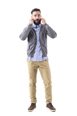 Cool relaxed funky hipster in cardigan adjusting mustache and looking away. Full body length portrait isolated on white studio background. 