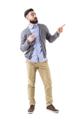 Uncertain confused bearded man pointing fingers up and looking above. Full body length portrait isolated on white studio background. 