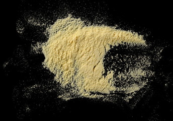 Corn flour pile isolated on black background, top view