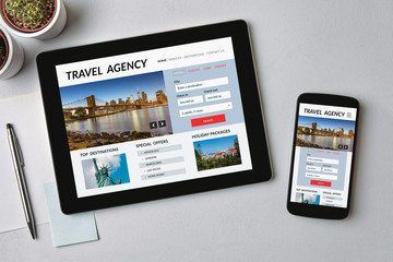Travel agency concept on tablet and smartphone screen over gray table. All screen content is designed by me. Flat lay
