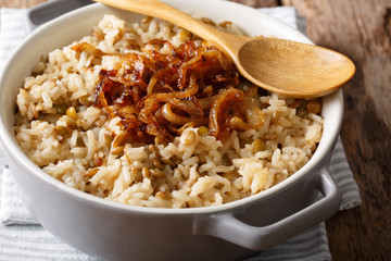 Stewed rice with lentils and fried onions close-up in a bowl. horizontal