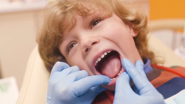 baby boy with curly red hair in blue dental chair. Children's dentist