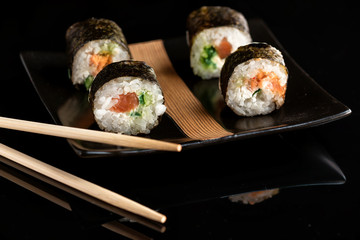 Japanese rolls on a black plate with ginger