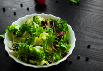 various fresh mix salad leaves with lettuce, radicchio, and rocket in bowl on dark wooden background