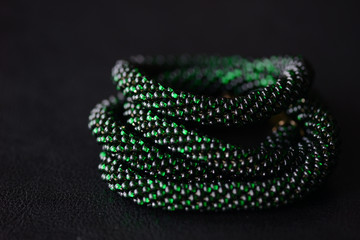 Bead crochet necklace green color on a dark background close up