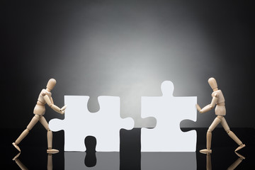 Two Wooden Dummies Solving Jigsaw Puzzle
