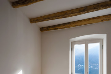 Empty room with large windows and antique beams