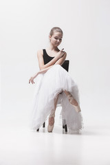 Fototapeta na wymiar The teen ballerina in white pack sitting on chair