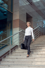 Business woman in pants with briefcase walking on stairs