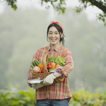農園で野菜を持ち微笑む女性