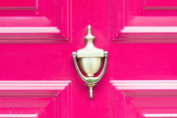 Knocker. Old antique golden knocker on the abstract pink wooden doors for knocking close up