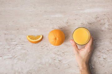 Fototapeta na wymiar cropped image of man taking glass of fresh orange juice from table