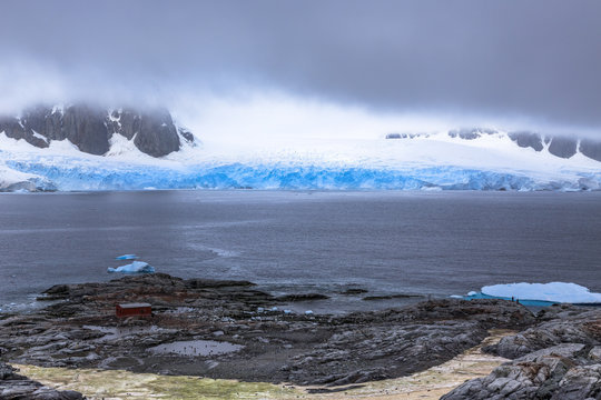 Rocky coastline fjord panorama with mountains, clouds and blue glacier, Peterman island, Antarctic peninsula