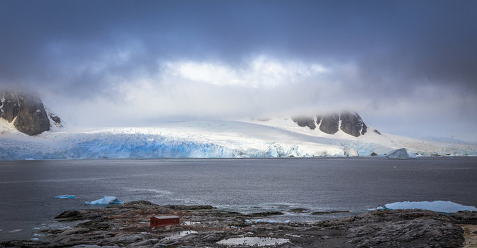 Rocky coastline panorama with mountains and glaciers hidden in clouds, Peterman island, Antarctic peninsula