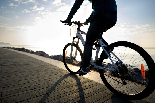cyclist riding bike in the sunrise coast path