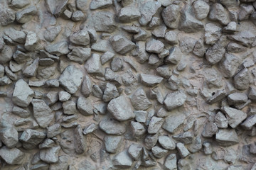 Crushed stone. The texture of the stones on the wall. Background of pebbles on a concrete surface.