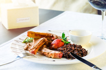 Grilled Rack of Lamb served in a plate with rosemary sauce and black rice, a dish in a restaurant