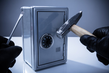 Thief Using Screwdriver And Hammer To Open Safe