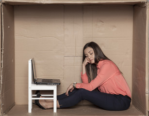 business woman sits down in a cardboard office