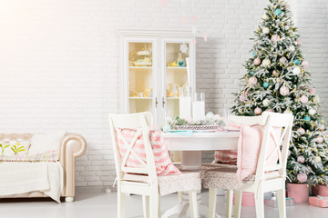 Beautiful Christmas decorated light living room with a Christmas tree, table and chairs. Concept of winter holidays and Happy New Year